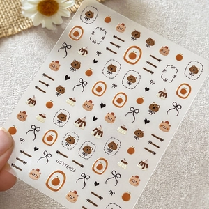 Autocollants d'ongles ours gélifiés et nœuds noirs aux motifs orange et crème