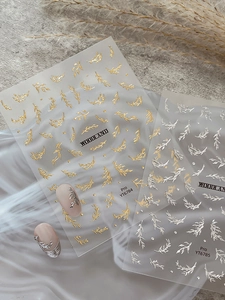 Detailed view of gold and silver metallic leaf nail art stickers with embossed textures