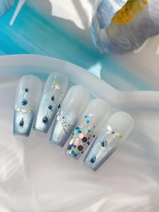 Macro detail of ice blue cat-eye nails with crystals, sequins and metal chain