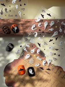 Detail of Halloween nail art stickers with ghosts, bats, and stars on nails
