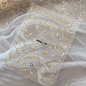 Elegant gold foil leaf nail art stickers with Woodland design on white textured background