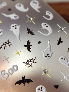 Macro shot of 3D embossed Halloween ghost and bat nail art stickers with sparkly rhinestones