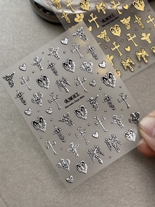 Detail von 3D-Metalleffekt-Nagelstickern mit goldenen und silbernen Engel- und Kreuzmotiven