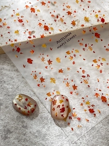 Detailed view of autumn maple leaf nail art stickers with orange and red foliage patterns