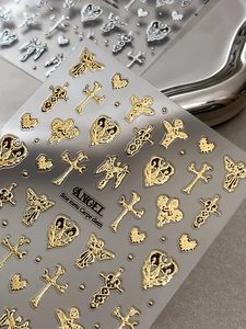 Makrodetail gotischer Engel- und Kreuz-Nagelsticker mit Gold- und Silberprägung