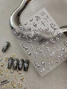 Nahaufnahme von 3D-Gothic-Nagelstickern aus Metall mit Totenkopf auf grauem Tablett
