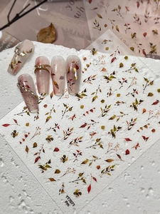 Detailed view of autumn leaf nail stickers on nude gradient nails with gold frame accents
