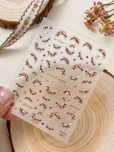 Close-up of autumn-themed nail stickers with maple leaves, dried flowers, and crystal accents