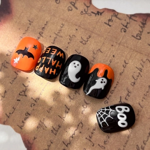 Halloween press-on nails featuring orange and black ghost designs with bat and star patterns