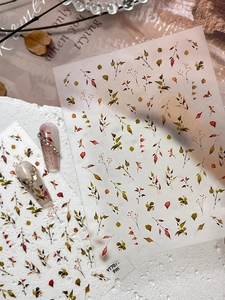Detail view of leaf nail art stickers with autumn foliage designs and pearl accents