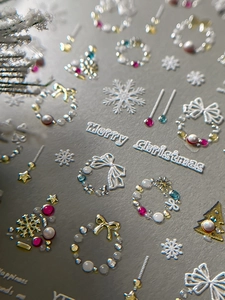 Macro detail of 5D embossed Christmas nail stickers with pearl snow and wreath textures