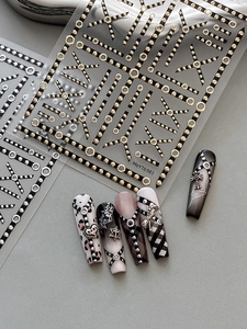 Close-up of gold and silver metallic nail stickers with punk crosses and chain patterns