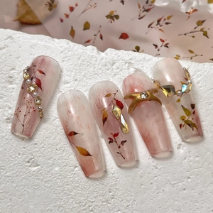 Long coffin press-on nails with pink blush gradient, maple leaves, and crystal rhinestones