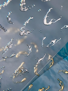 Macro view of 3D liquid metal nail stickers with gold and silver organic drop shapes
