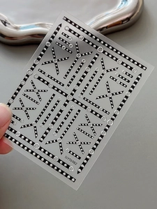 Detail of silver metallic dot and black line geometric patterns on nail art sticker