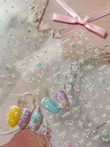 Detailed close-up of shell-finish bow and star nail art stickers on various manicures