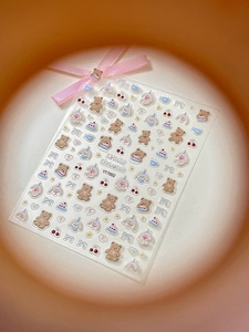 Macro shot of 3D embossed nail art stickers featuring cute cartoon bears and cakes