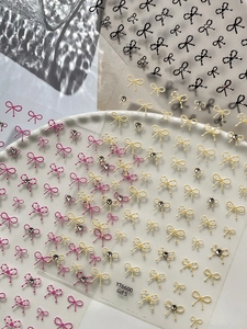 Close-up of embossed 3D bow nail stickers with rhinestone accents and pearl details
