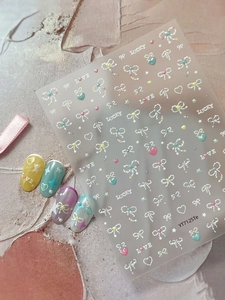 Macro detail of pearlescent bow and star nail stickers with 3D texture on pink background