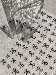 3D nail stickers featuring black beaded bows with rhinestones on sparkling press-on nails
