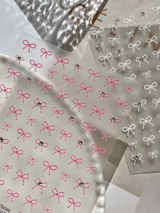Macro view of 3D embossed bow nail stickers with fine pearl texture and crystal rhinestones