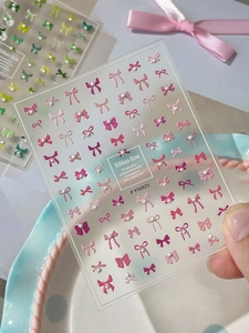 Makrofoto von 3D-Präge-Nagelstickern mit rosa Schleifen und Perlenverzierung auf der Packung
