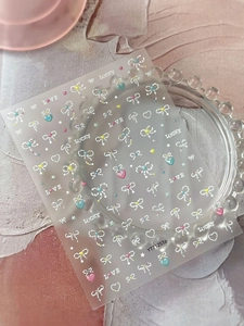Close-up of 5D embossed nail stickers featuring stars and bows on a glass tray