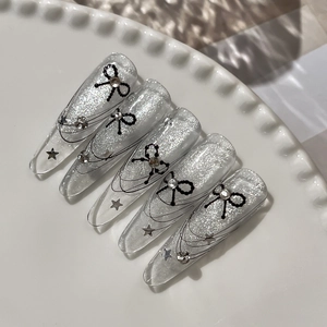 Stiletto press-on nails with silver glitter gradient, black bows and star accents
