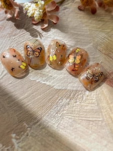 Macro shot of 5 amber marble nail tips with hand-painted realistic butterfly patterns