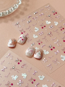 Macro detail of 3D nail art stickers featuring pink bows, rabbits and cherry designs