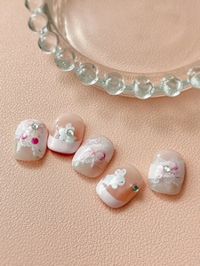 Macro view of press-on nails with 3D white bunnies, pink bows, and cherry accents