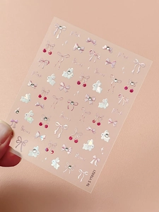 Macro detail of pink bow and white rabbit nail art stickers with sparkly rhinestones