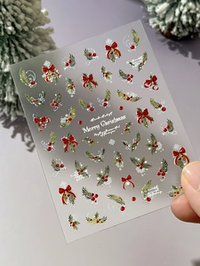 Macro shot of 3D Christmas nail stickers with metallic Merry Christmas text and snowflakes