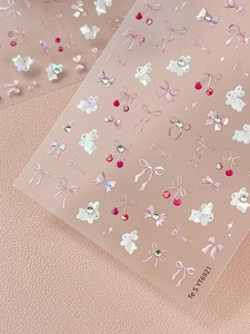 Detailed macro view of 3D embossed pink bow and rabbit nail art stickers with rhinestones
