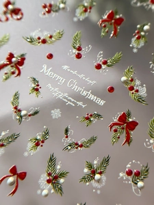 Macro shot of 3D embossed Christmas nail stickers with red bows and holly berry motifs