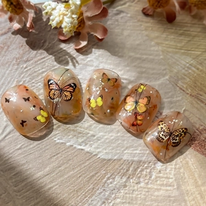 Realistic butterfly embossed nail stickers in amber orange with gold foil accents