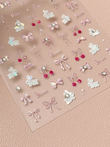 Macro shot of 3D bunny and bow nail stickers with rhinestones on pink leather background