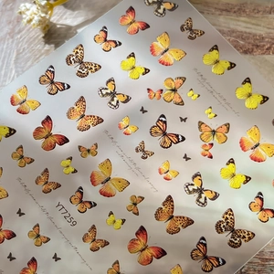 Realistic butterfly nail art stickers in warm yellow and orange tones on wood background