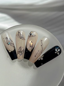 Macro detail of coffin shaped press-on nails with black butterfly art and sparkling rhinestones