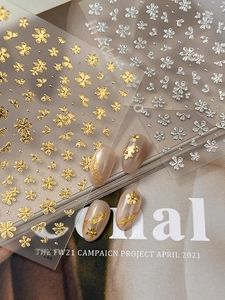 Macro shot of 3D embossed gold floral nail art stickers with metallic texture details