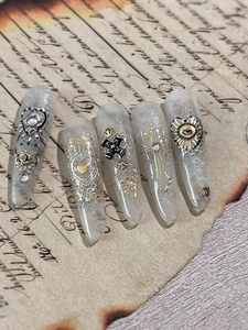 Detail of baroque nail art stickers featuring gold crosses and silver hearts motifs