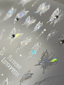 Macro detail of 3D butterfly nail stickers with holographic shimmer and rhinestone accents