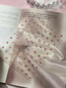 Macro detail of 3D embossed nail art stickers with pink and yellow gradient flowers