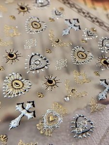Macro view of 3D embossed gothic nail stickers with gold and silver heart cross motifs