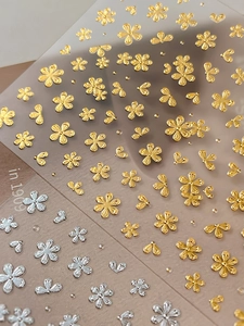 Detailed close-up of 3D embossed metallic flower nail stickers in gold and silver colors