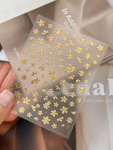 Detail of 3D embossed gold flower nail art sticker with metallic texture on hands