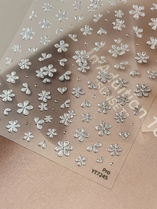 Close-up of 3D metallic silver flower and heart nail stickers on high-quality paper