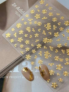 Detail of 3D embossed gold floral nail stickers with premium metallic luster on pink nails