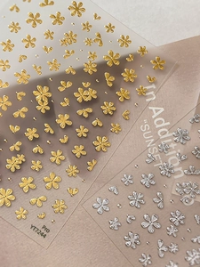 Macro shot of 3D embossed gold and silver floral nail stickers with metallic relief textures