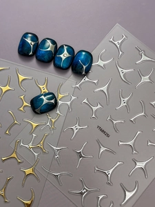 Detail of metallic silver and gold 3D star stickers on blue cat-eye nail art